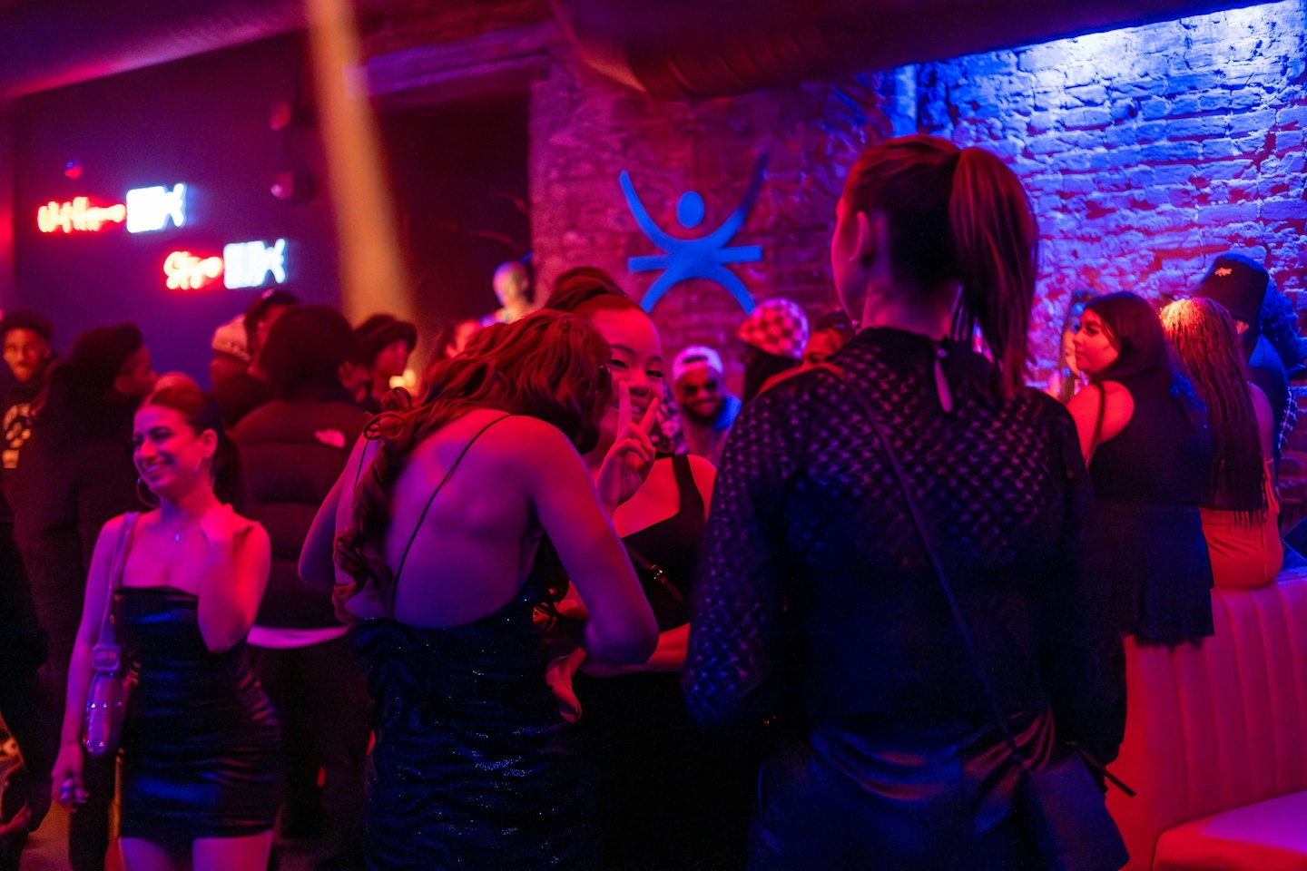 Group of friends laughing and dancing in a neon nightclub.