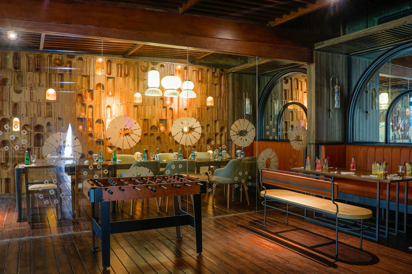 Modern restaurant interior with wooden booths and a foosball table.