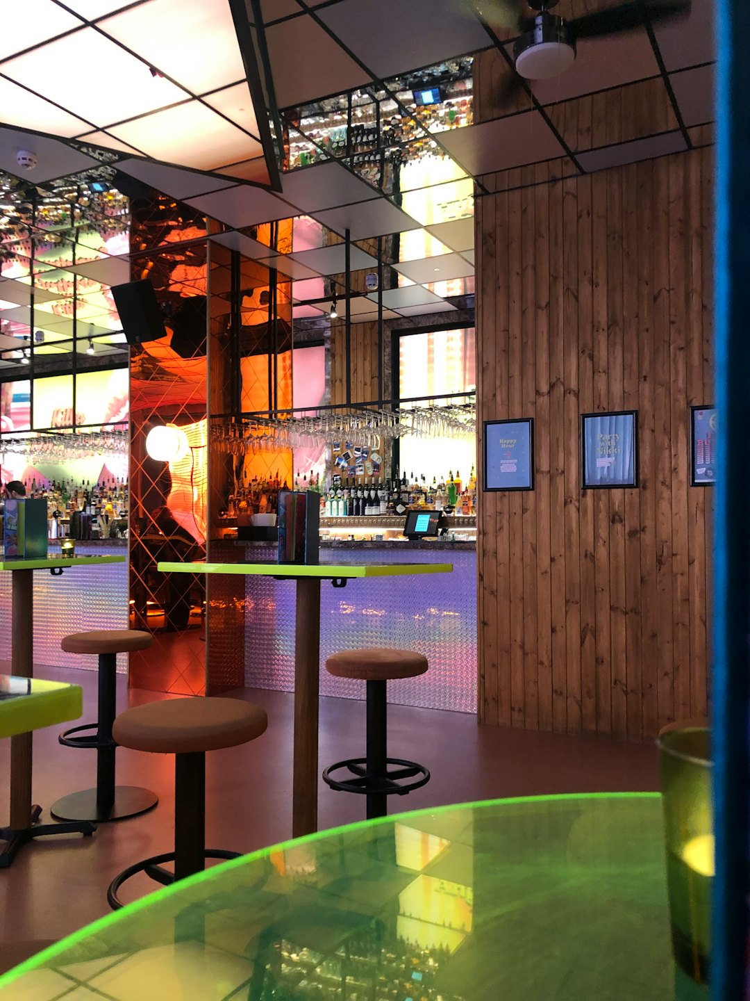 Modern bar with green tables and a stocked counter.